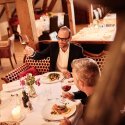 Gäste beim Abendessen stossen mit Rotweingläsern im Restaurant Haberbüni an